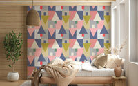 Geometric Forest Harmony wallpaper of triangle trees behind a wood daybed with striped bedding