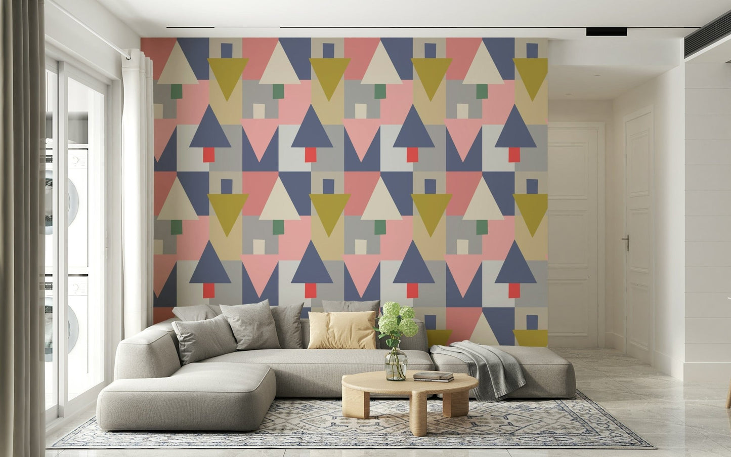 Geometric Forest Harmony wallpaper in pink and mustard triangles behind a grey sectional and wood table
