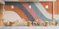 Abstract Waves wallpaper mural in orange, pink and teal in a cafe with rattan chairs, tables and woven pendant lamps