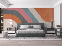 Abstract Waves wallpaper mural in orange, pink and teal in a bedroom behind a green bed with gray bedding