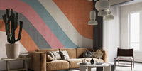 Abstract Waves wallpaper mural in orange, pink and teal behind a tan velvet sofa and cactus in a living room