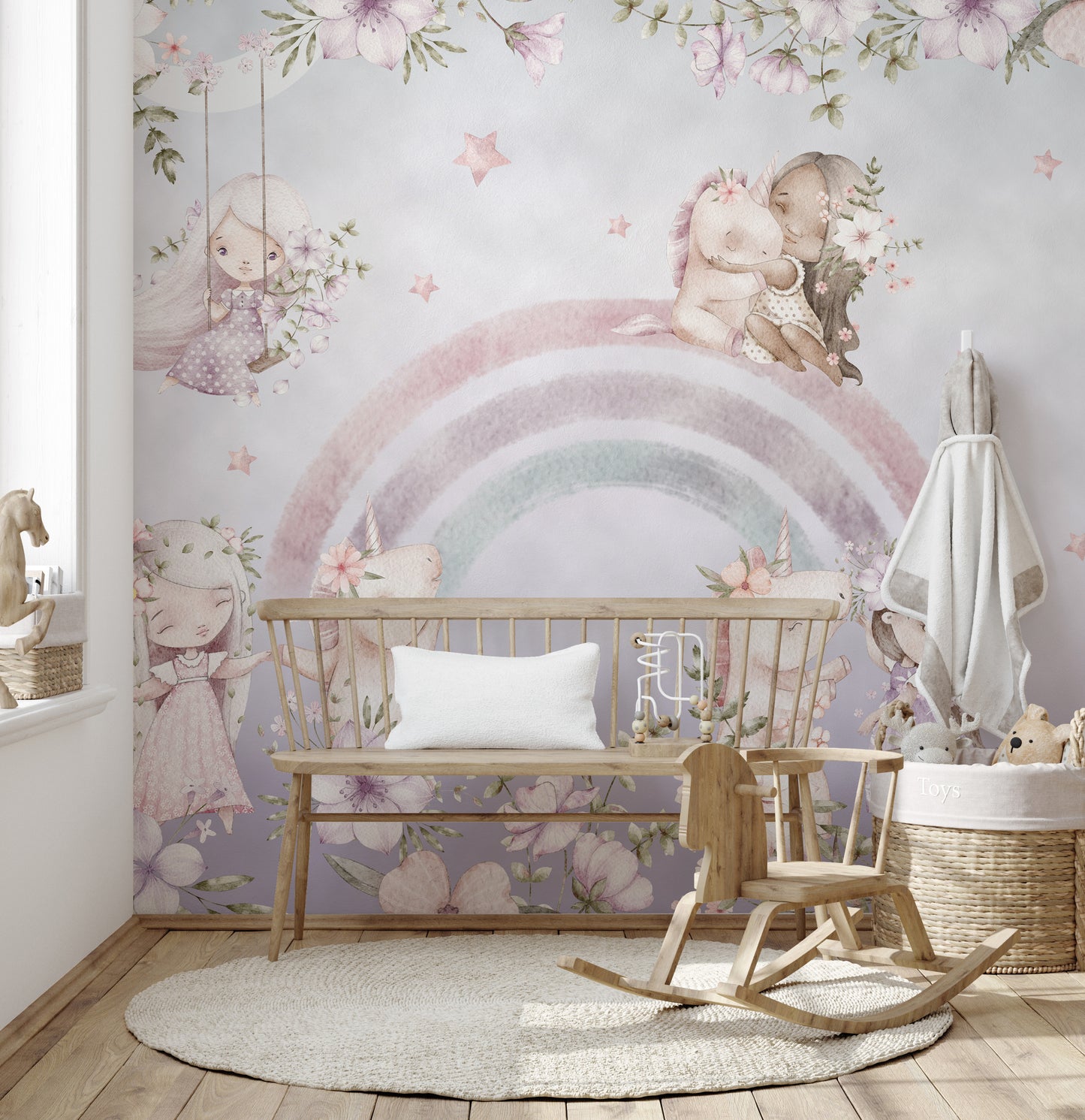 Whimsical Rainbow wall mural in a pastel nursery with a wood bench, rocking chair and round woven rug