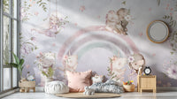 Whimsical Rainbow wall mural with pastel unicorns and fairies in a girls room with floor cushions and a wood nightstand