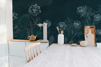 Midnight Botanical wallpaper mural of navy florals in a kitchen with pale wood table, white cabinets and cutting boards