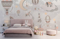 Starry Circus Spectacle mural in soft pink behind a child's upholstered bed with bunny and teddy in a nursery bedroom