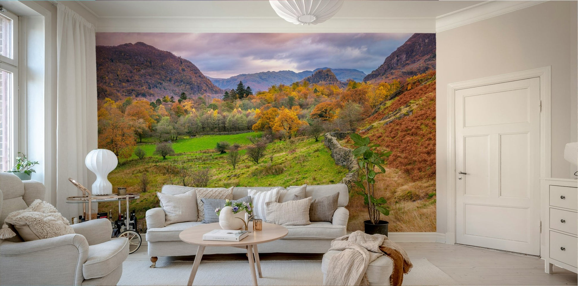 Golden Hills wallpaper mural of an autumn valley with green meadow and rugged hills at dusk behind a beige sofa in a living room