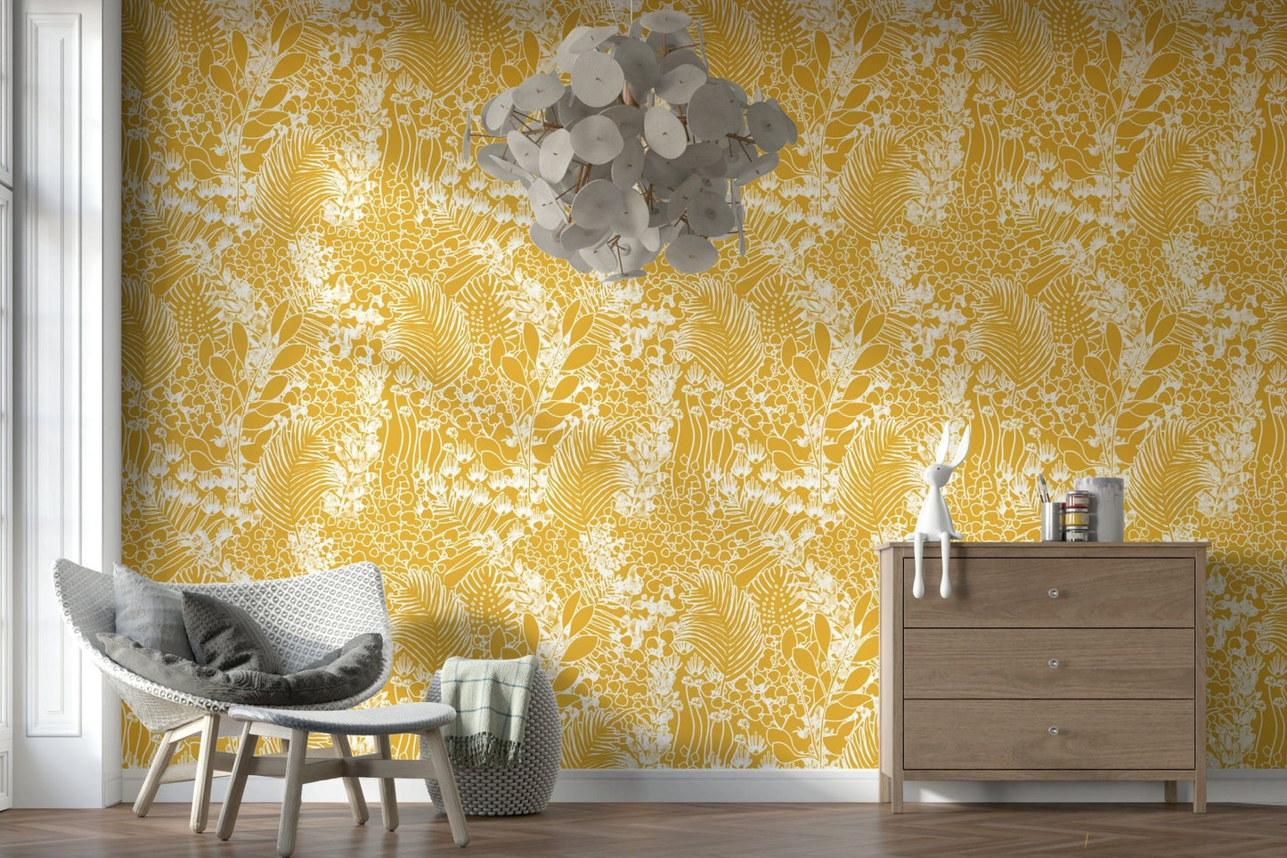Golden Meadow Dream wallpaper in yellow ferns behind a grey woven lounge chair and wooden dresser