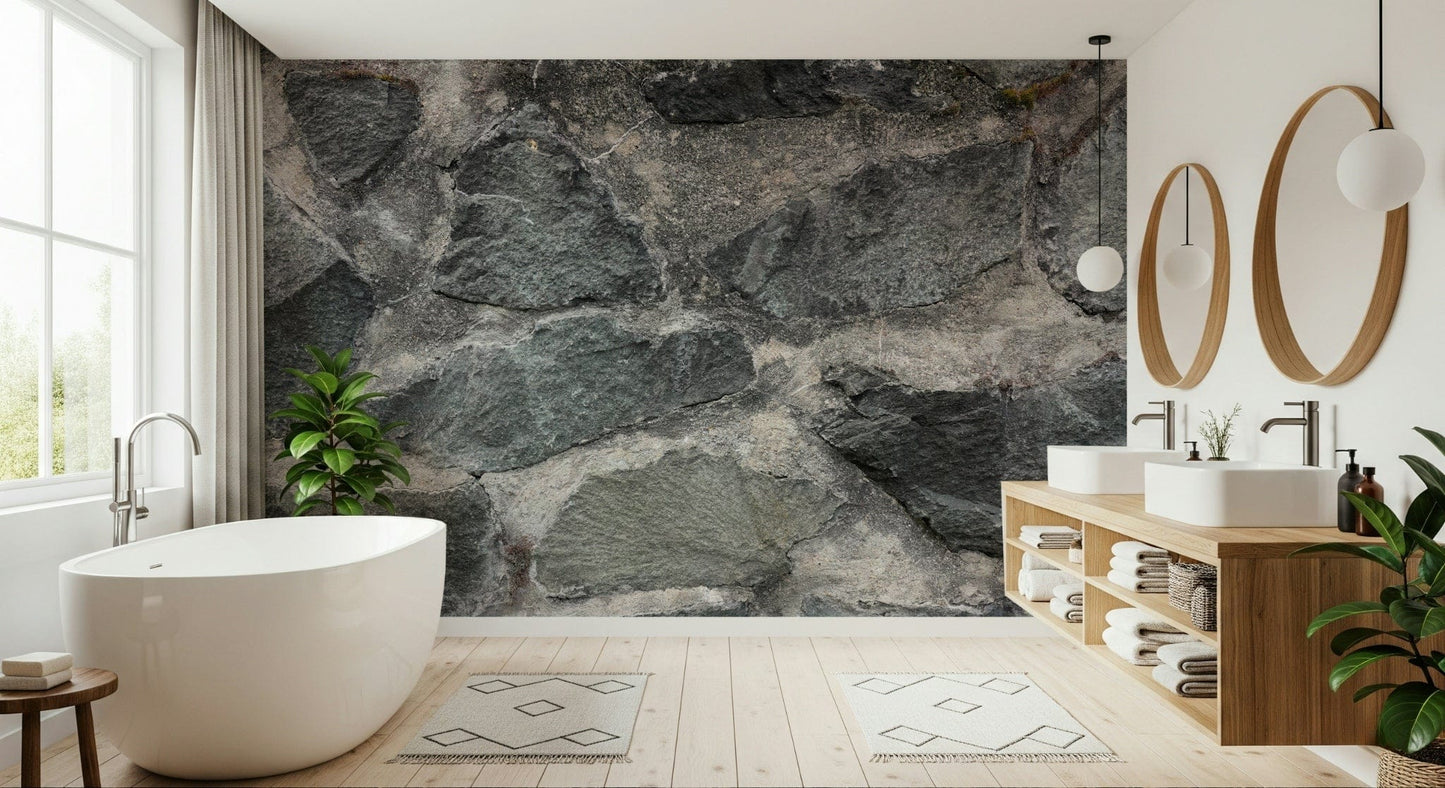 Granite Blocks wallpaper mural of grey stone masonry behind a white freestanding tub and wood vanity in a bathroom