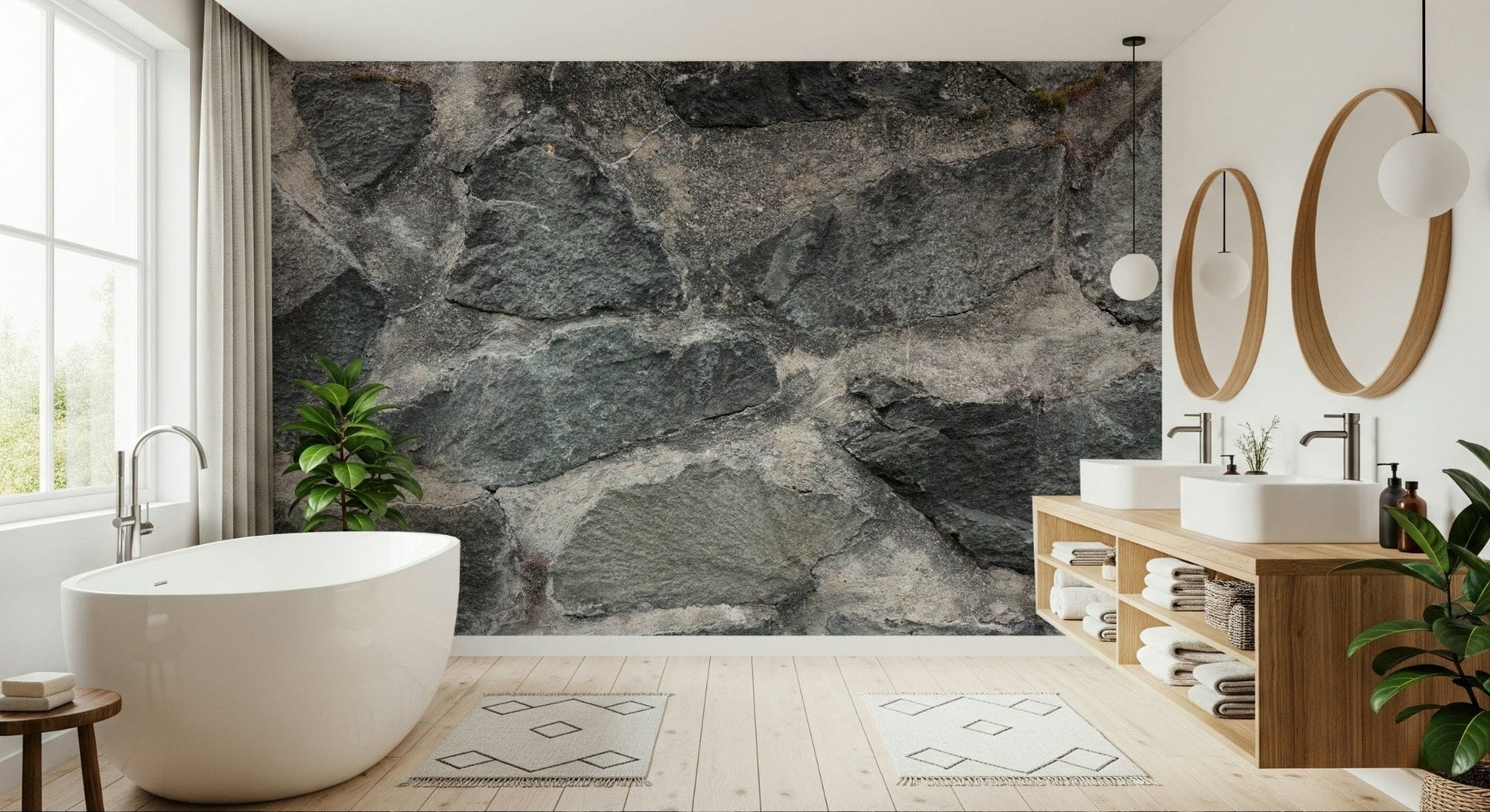 Granite Blocks wallpaper mural of grey stone masonry behind a white freestanding tub and wood vanity in a bathroom