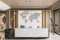 Gray Watercolor World Map wallpaper mural in soft gray behind a marble reception desk with two iMacs