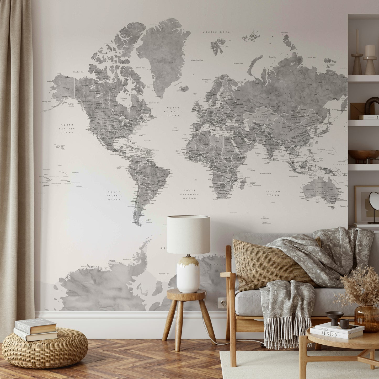 Gray Watercolor World Map wallpaper mural in soft gray behind a grey sofa with a lamp on a wood stool