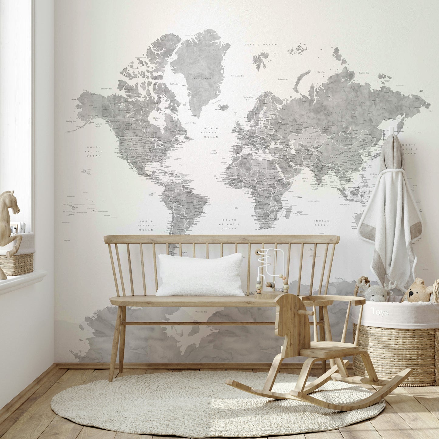 Gray Watercolor World Map wallpaper mural in soft gray above a wooden bench and rocking horse in a nursery