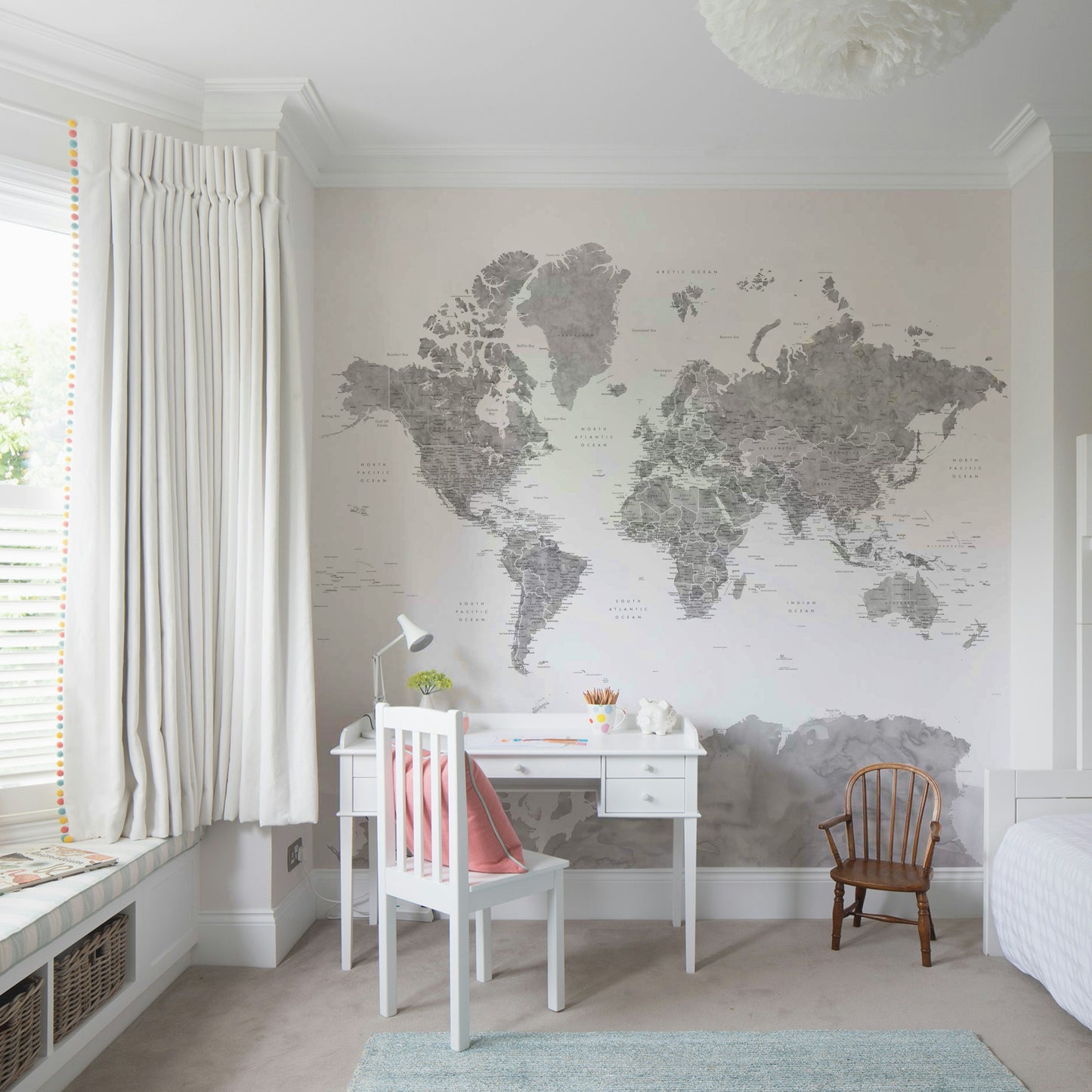 Gray Watercolor World Map wallpaper mural in soft gray behind a white desk and chair in a kids bedroom