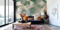 Ethereal Brushstrokes wallpaper mural in green and cream behind a navy sofa with orange pillows and a persian rug