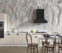 Grunge Gleam wallpaper mural with beige and grey leaves behind a cream kitchen with black range hood and dining chairs