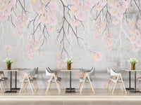 Hanging pink flowers wallpaper mural with pink blooms on grey behind cafe-style wood tables and grey chairs
