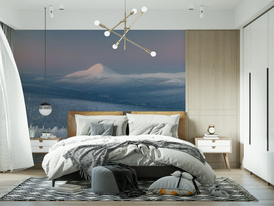 Icy Mountain Dreams wallpaper mural of a snowy peak at dusk behind a tan bed with a gold sputnik chandelier