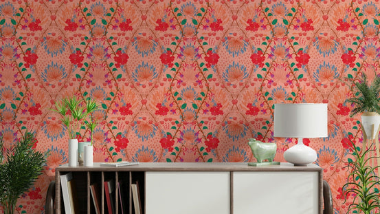 Indian Summer wallpaper in coral with red blooms behind a wooden sideboard, white lamp and trailing plants