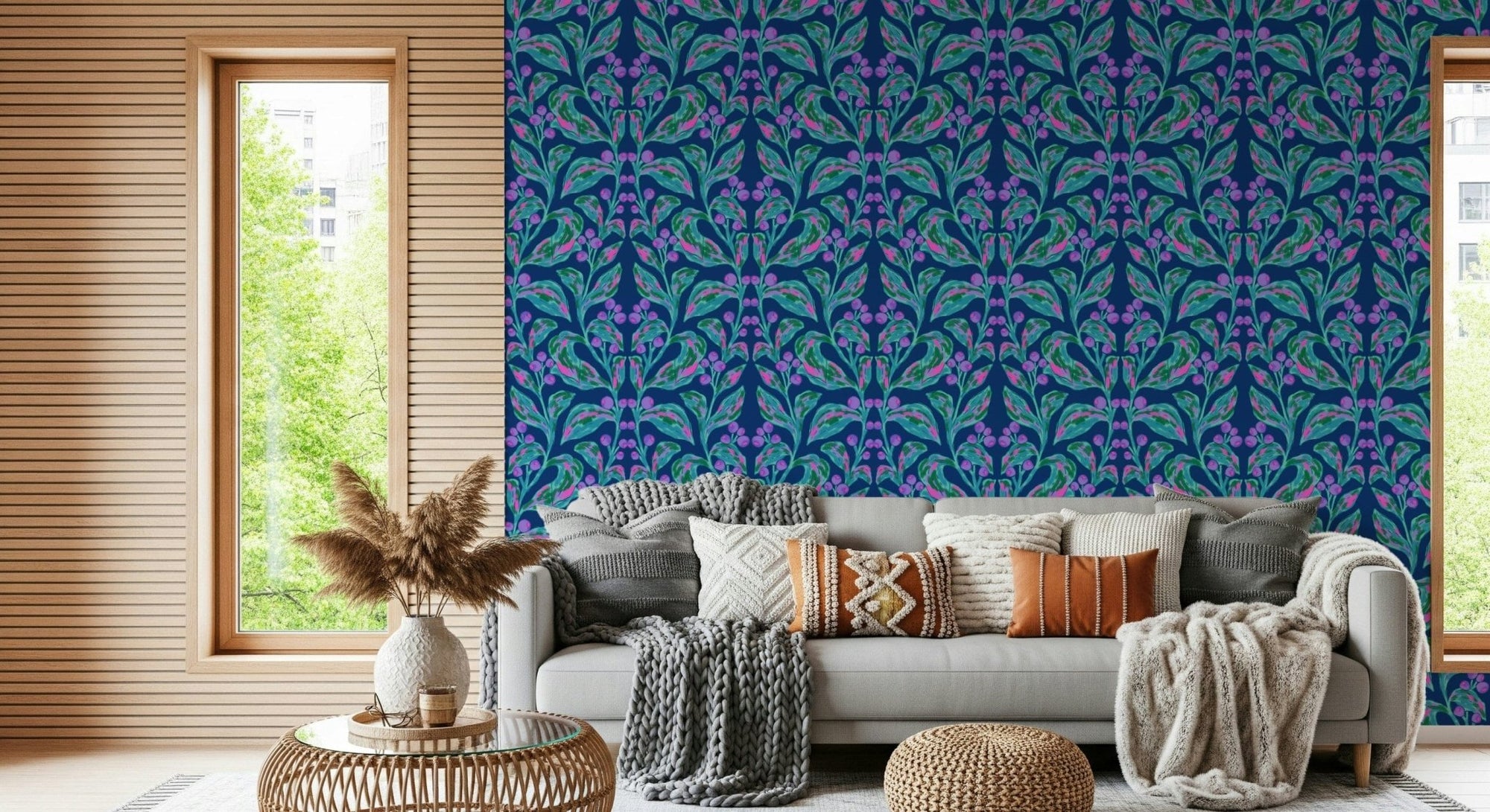 Indigo electric leaves wallpaper of teal and purple botanical motifs behind a grey sofa with knit cushions