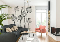 Ink Poppy Pods wallpaper mural of black ink pods behind a charcoal sectional and coral armchair in a living room