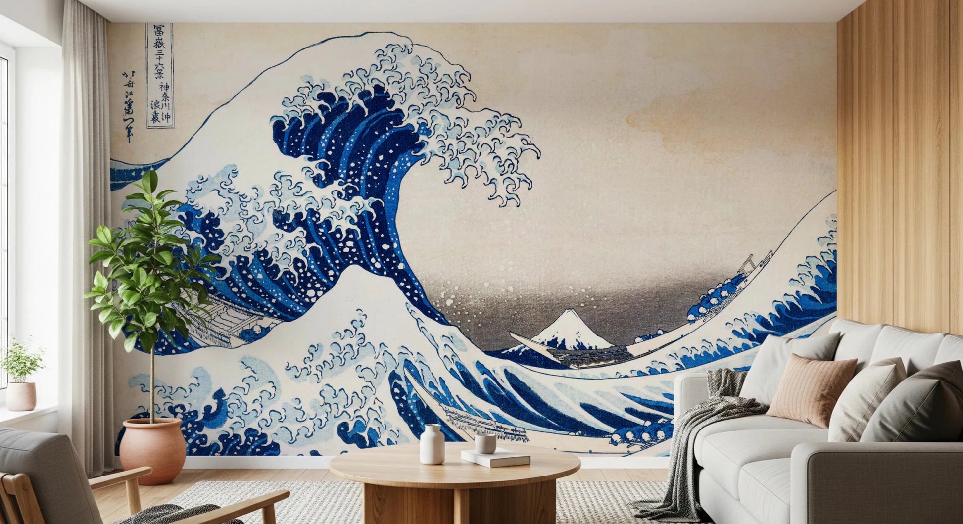 Katsushika Hokusai's The Great Wave off Kanagawa wallpaper mural of the blue wave behind a grey sofa and round wooden table in a living room