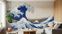 Katsushika Hokusai's The Great Wave off Kanagawa wallpaper mural of the blue wave behind a grey sofa and round wooden table in a living room