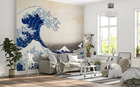 Katsushika Hokusai's The Great Wave off Kanagawa wallpaper mural with the blue wave behind a cream sofa and white wire chair in a living room