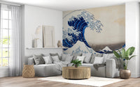Katsushika Hokusai's The Great Wave off Kanagawa wallpaper mural with the blue wave behind a grey sectional sofa and round wooden table
