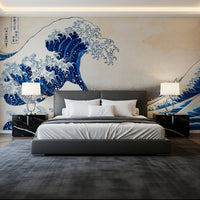 Katsushika Hokusai's The Great Wave off Kanagawa wallpaper mural with the blue wave above a grey bed and black marble nightstands in a bedroom