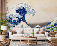 Katsushika Hokusai's The Great Wave off Kanagawa wallpaper mural of the blue wave behind a cream sofa and rattan chair in a living room