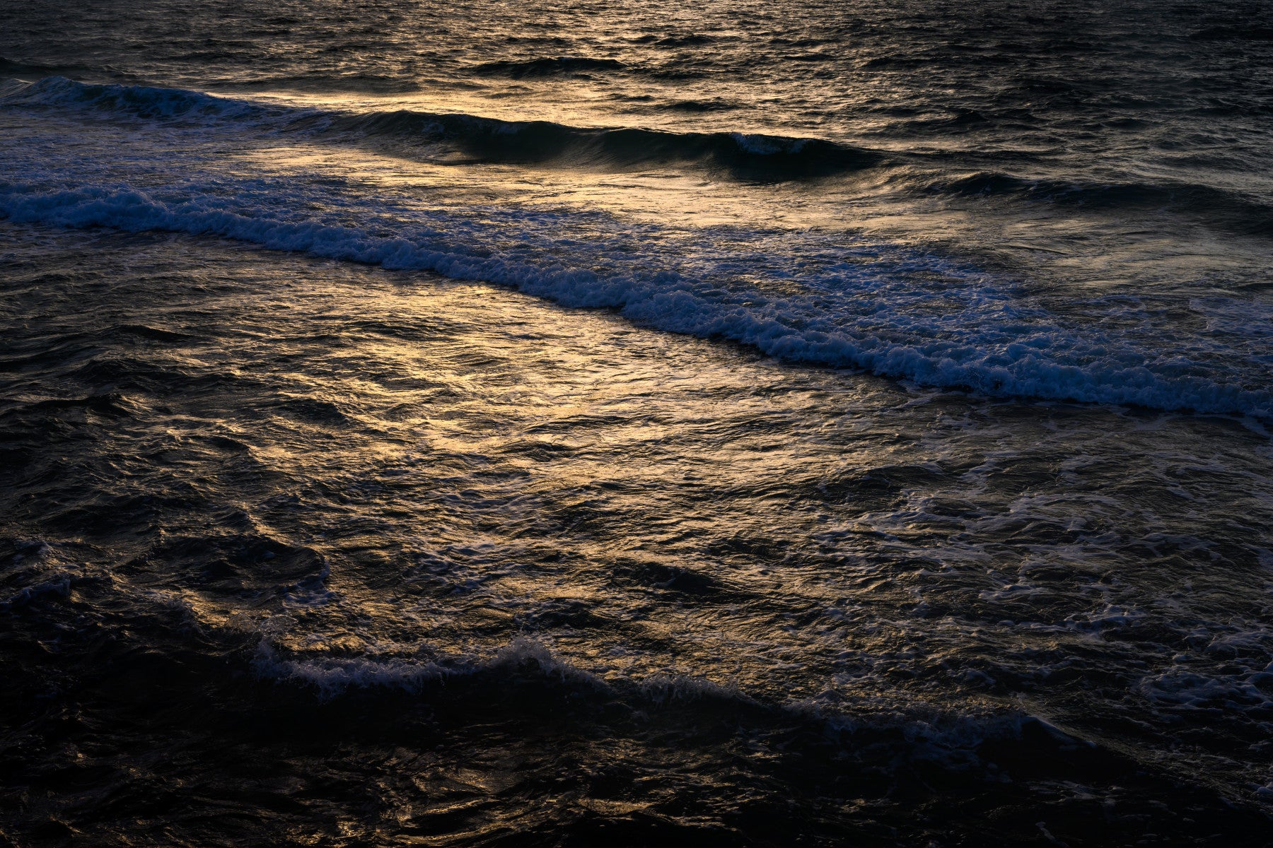 A close-up of the ocean water hitting the rugged rocks.


