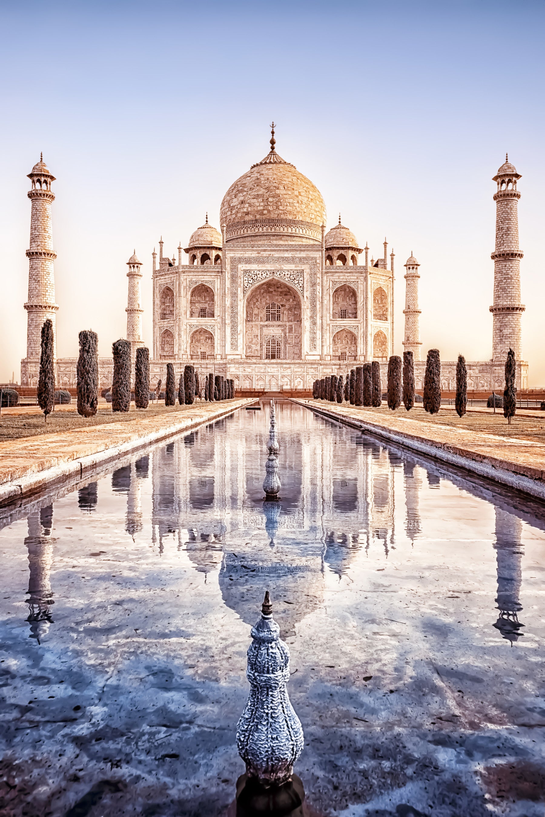 Eternal Taj wallpaper mural of the Taj Mahal and reflecting pool behind a bed and wood chair in a bedroom