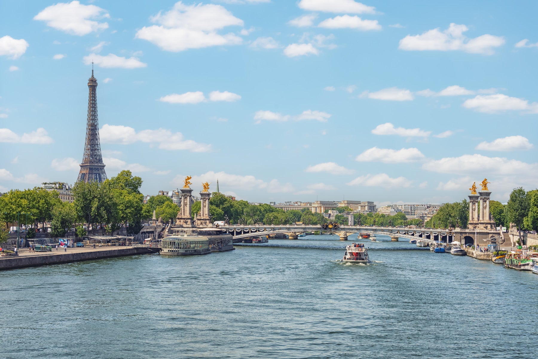 Seine Reflections wallpaper mural of the Eiffel Tower and river behind two white armchairs and a round wood table in a living room