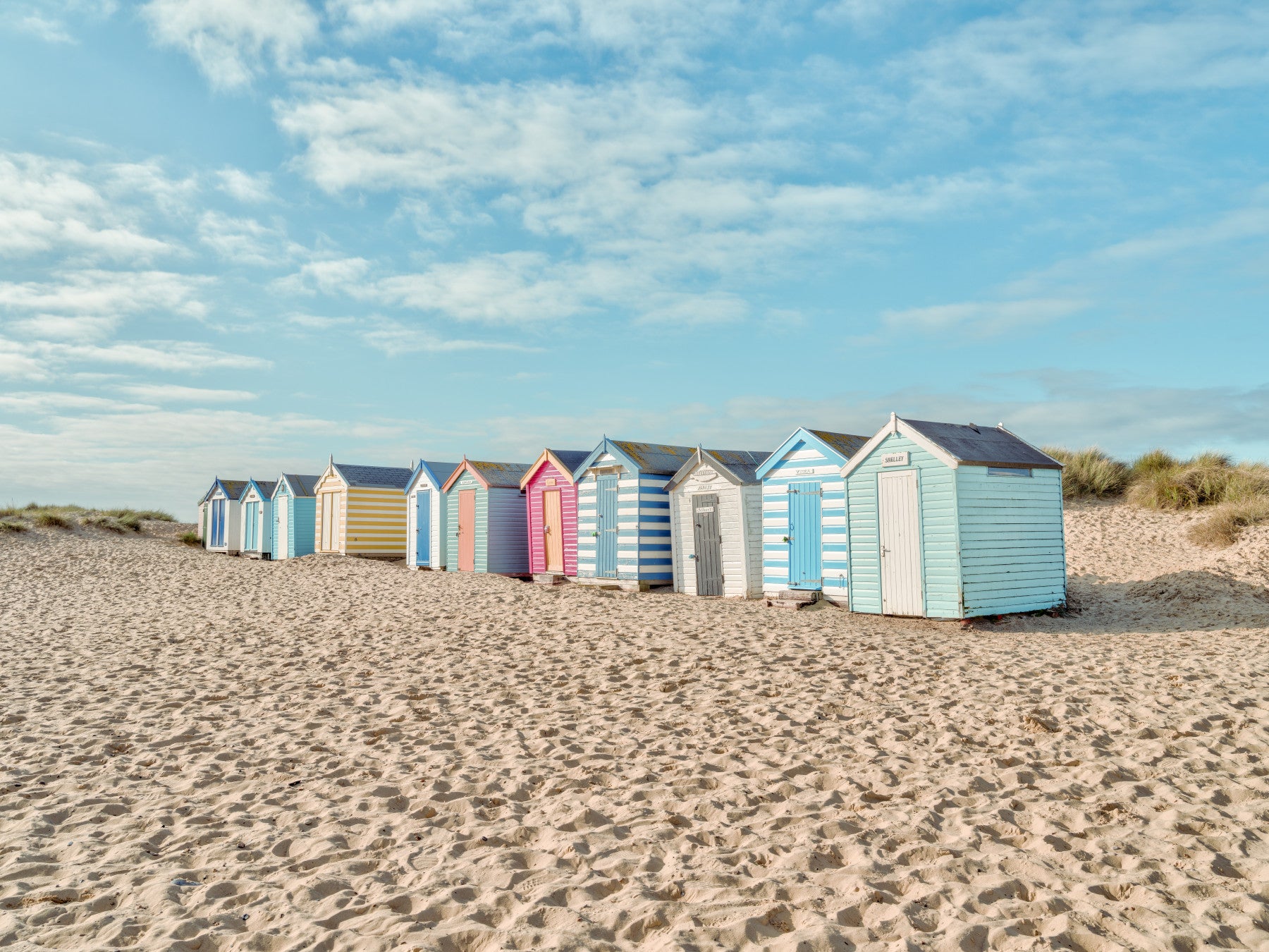 Colorful Beach Huts on the Shore living room Wall Mural with blue sky.