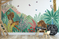 Leopard and Giraffe Kids wallpaper mural with a green jungle and butterflies behind a small desk in a playroom