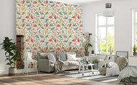 light Birdwatcher's wallpaper of pastel birds and leaves above a grey sofa with striped pillows in a living room