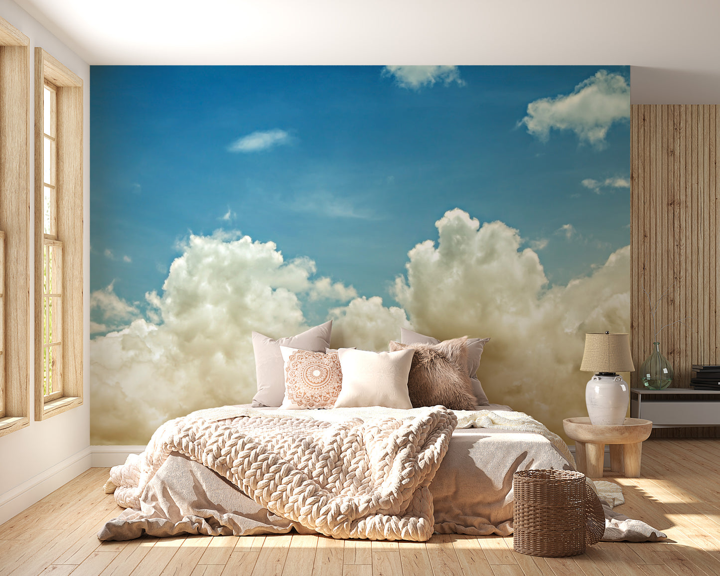 Light blue sky wallpaper mural of clouds behind a bed dressed in cream knit bedding in a bright bedroom