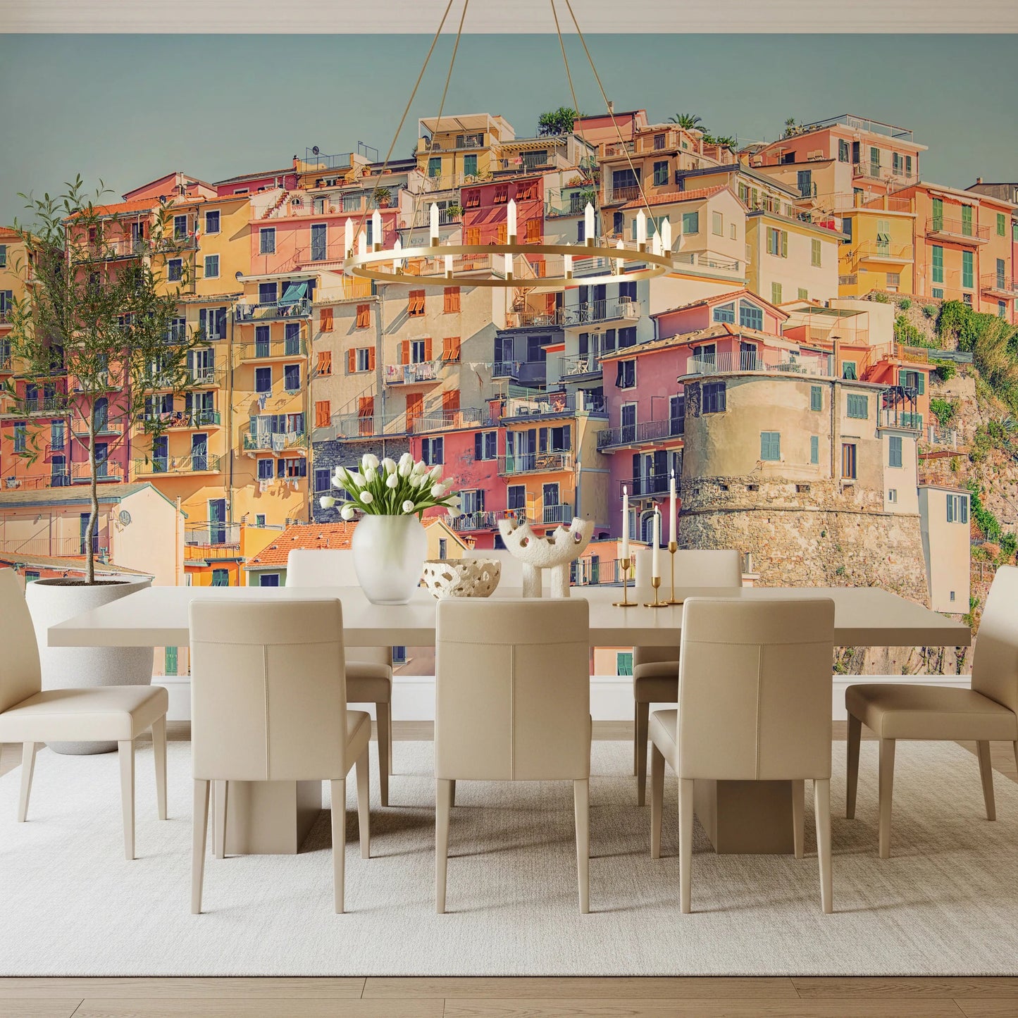 Manarola Vista wall mural of Cinque Terre houses behind a white dining table and gold ring chandelier