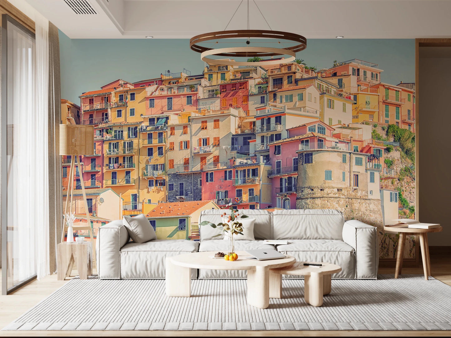 Manarola Vista wall mural of stacked pastel houses behind a white sofa and ring chandelier in a living room