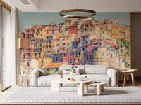 Manarola Vista wall mural of stacked pastel houses behind a white sofa and ring chandelier in a living room