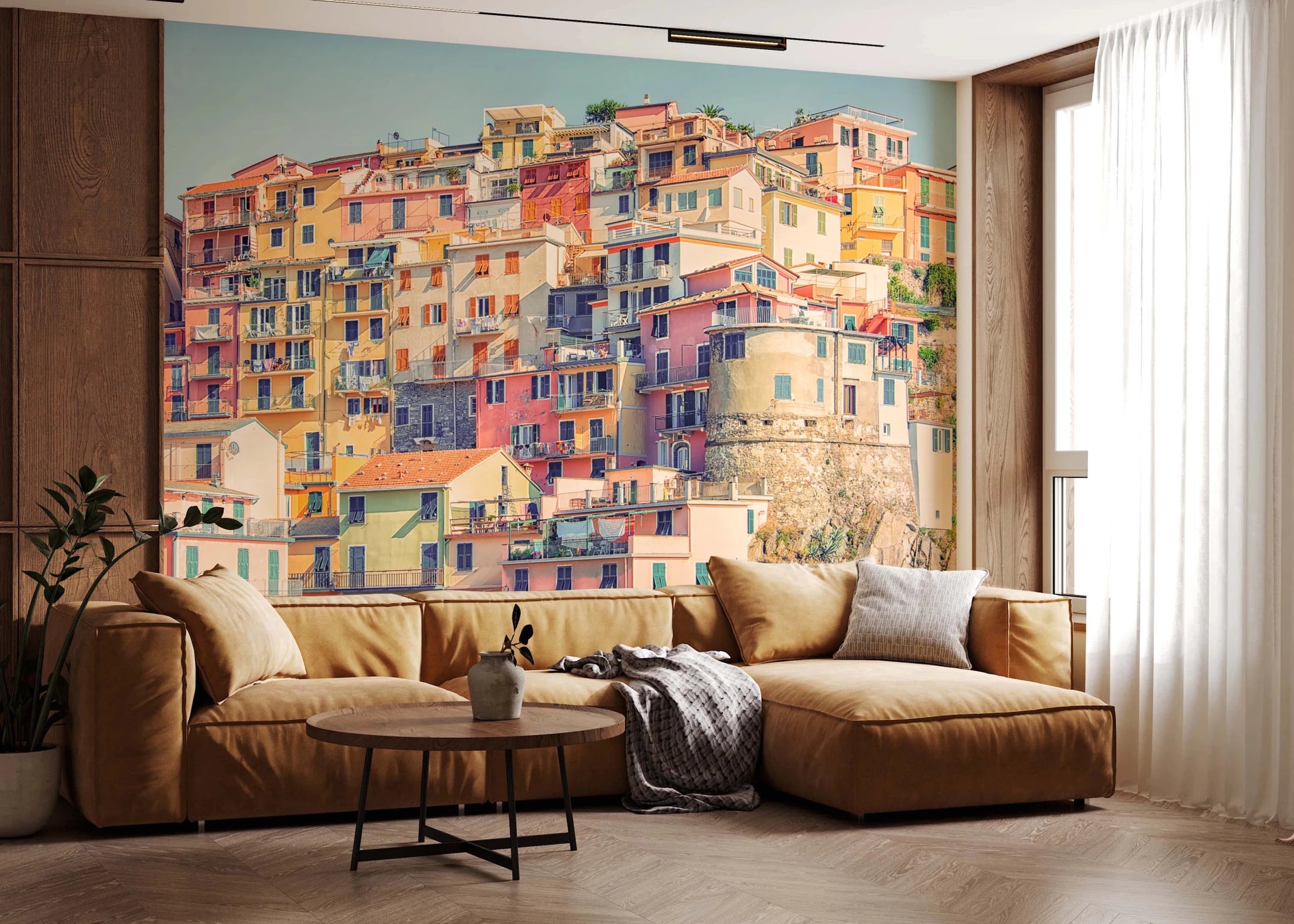 Manarola Vista wall mural of pastel hillside houses behind a camel leather sectional in a living room