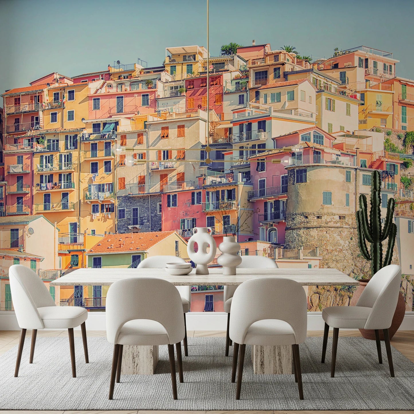Manarola Vista wall mural of colorful Cinque Terre houses behind a white dining table and cream chairs