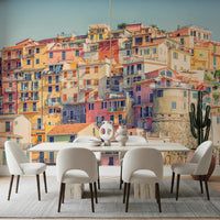 Manarola Vista wall mural of colorful Cinque Terre houses behind a white dining table and cream chairs