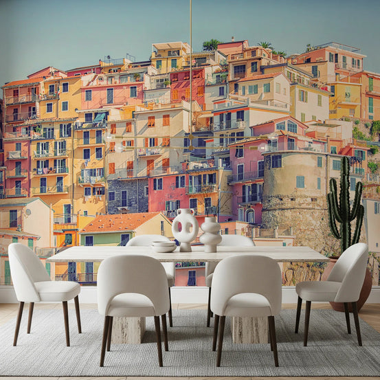 Manarola Vista wall mural of colorful Cinque Terre houses behind a white dining table and cream chairs