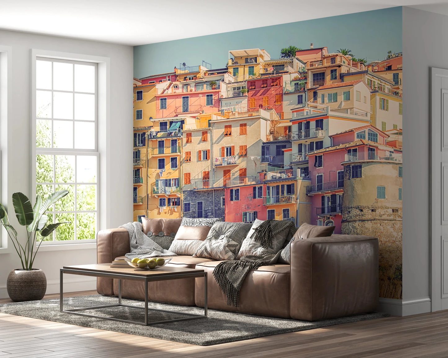 Manarola Vista wall mural of pastel cliffside houses behind a brown leather sectional in a living room