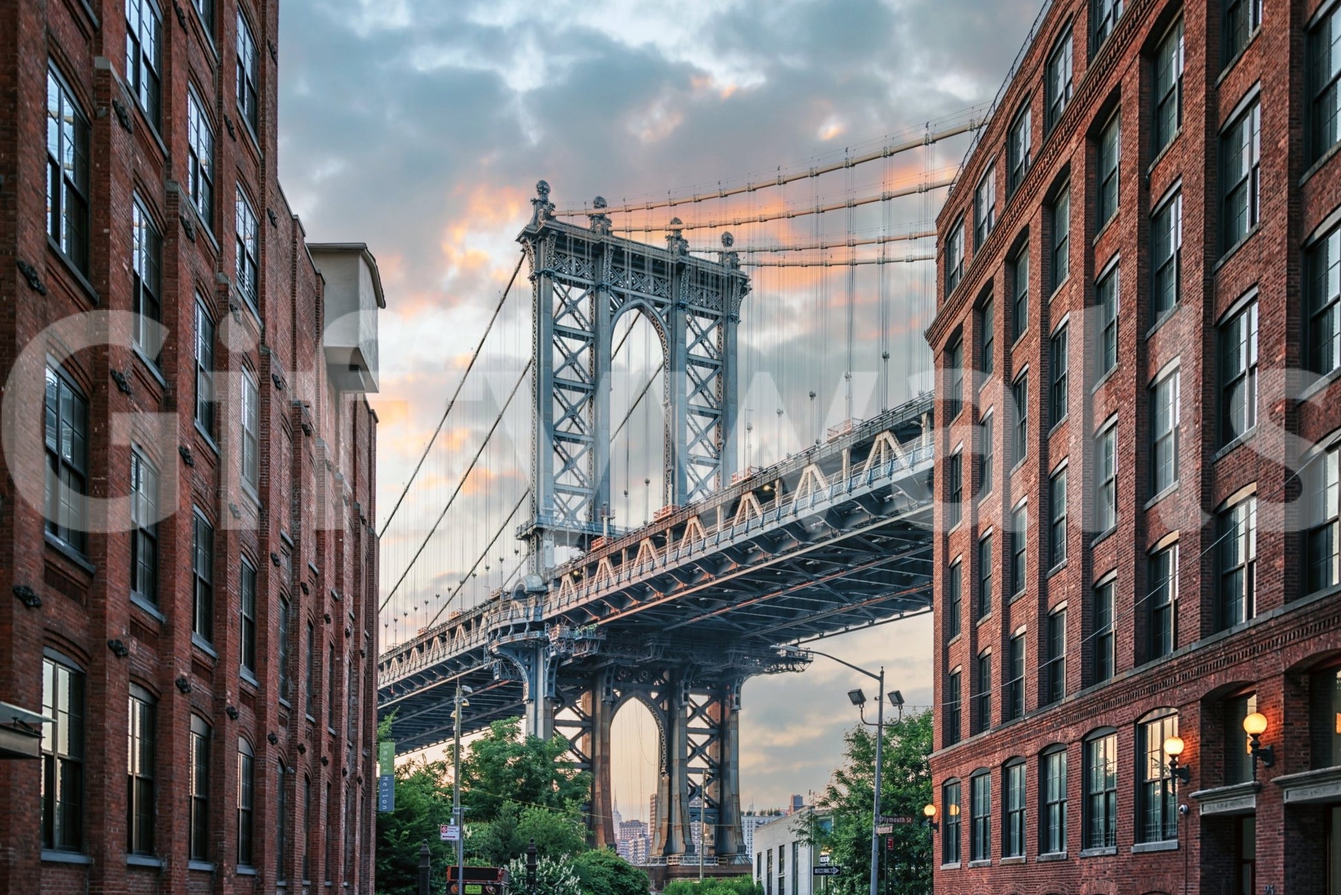Manhattan Bridge Vista wallpaper mural shown as a full-wall scene of the blue bridge tower framed by brick buildings at sunset