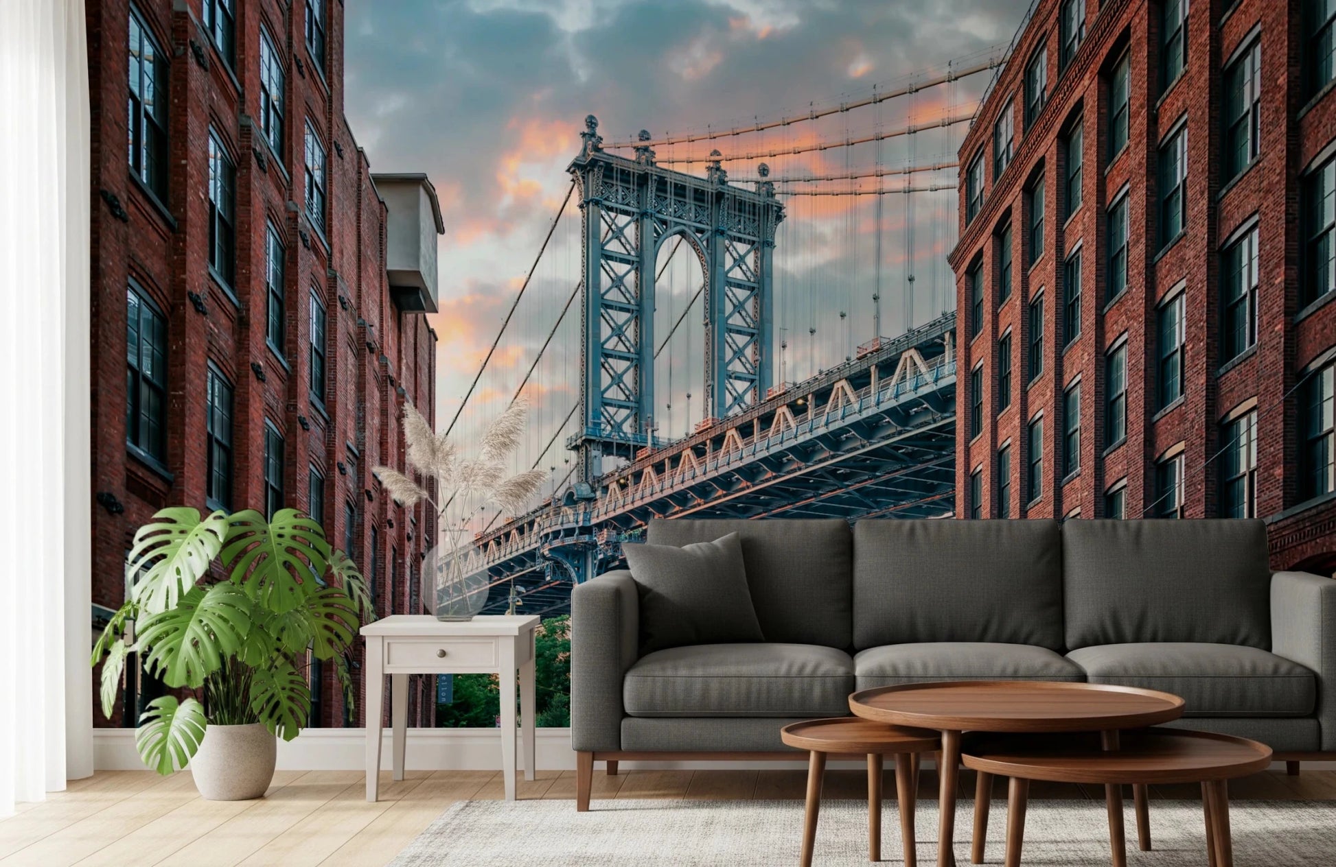 Manhattan Bridge Vista wallpaper mural of the bridge tower behind a grey sofa and round wood tables in a living room