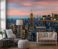 Manhattan Dawn wallpaper mural of the skyline behind a white crib and striped rocking chair in a nursery