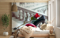 Masquerade Romance wallpaper mural with red mask, rose and heel behind a bedroom bed in peach bedding by a wood-panelled wall