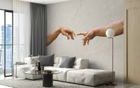 Michelangelos famous masterpiece wallpaper mural of two reaching hands behind a white sectional sofa in a living room